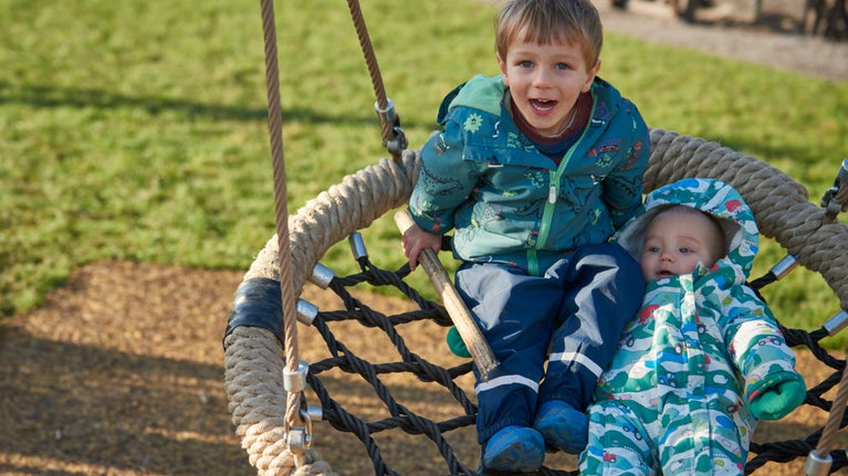 A child and a baby on a buddy swing